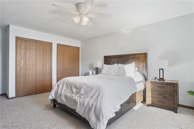 bedroom with two closets, ceiling fan, and light carpet