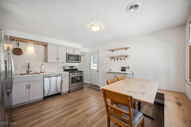 kitchen with appliances with stainless steel finishes, gray cabinetry, dark hardwood / wood-style flooring, and sink