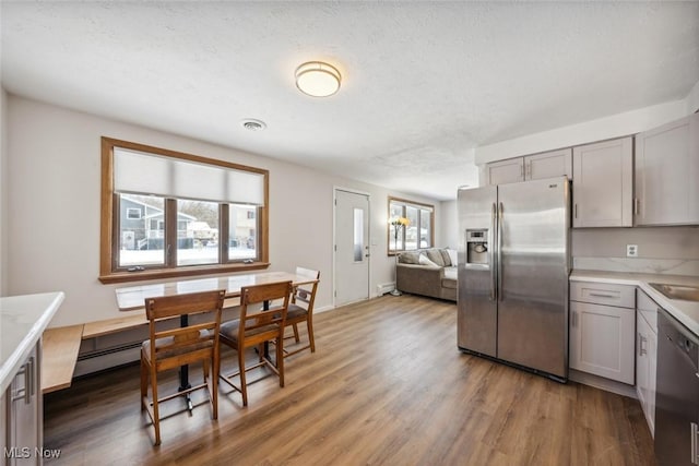 kitchen with stainless steel appliances, a textured ceiling, gray cabinets, and dark hardwood / wood-style flooring