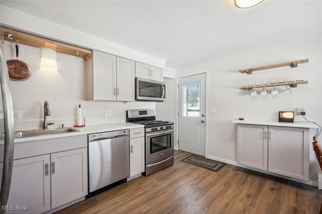 kitchen featuring sink, dark hardwood / wood-style flooring, gray cabinets, and appliances with stainless steel finishes