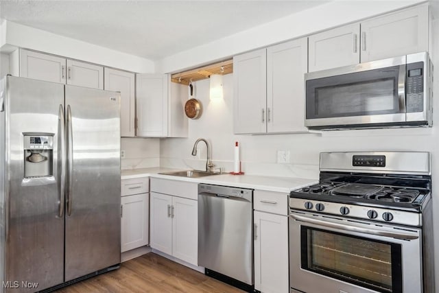 kitchen with sink, stainless steel appliances, light wood-type flooring, and white cabinets