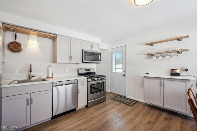 kitchen featuring stainless steel appliances, dark wood-type flooring, gray cabinetry, and sink