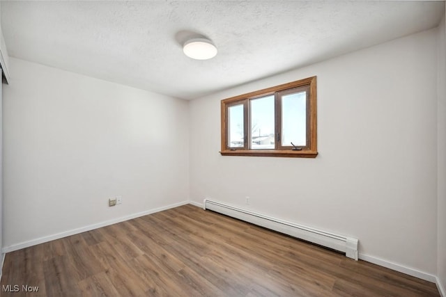 unfurnished room featuring a textured ceiling, baseboard heating, and dark hardwood / wood-style floors