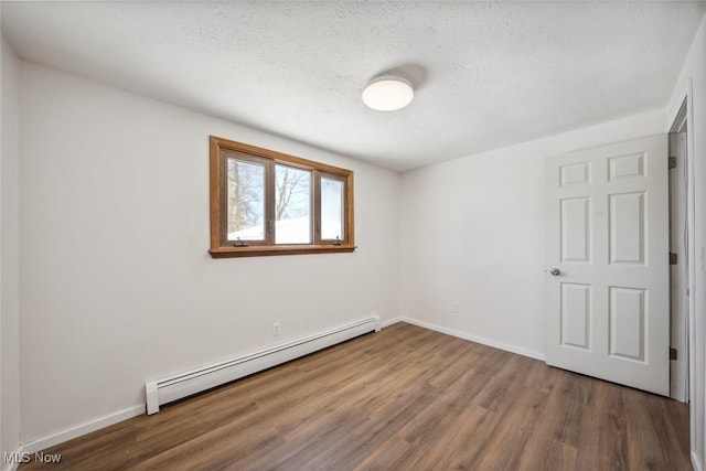 unfurnished room with a textured ceiling, dark hardwood / wood-style flooring, and a baseboard heating unit