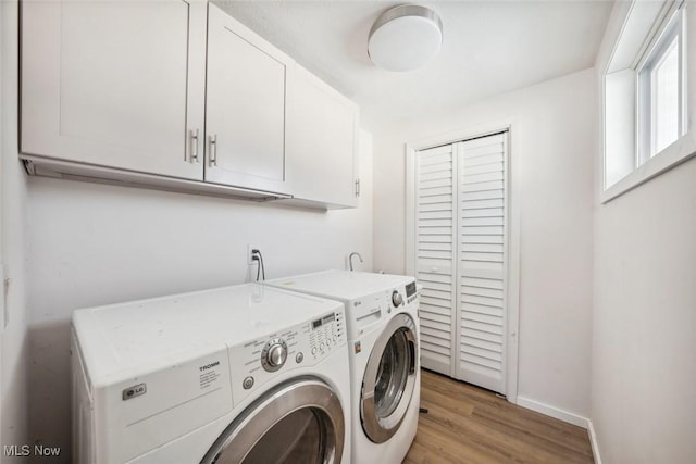 laundry room with washer and dryer, cabinets, and light hardwood / wood-style flooring