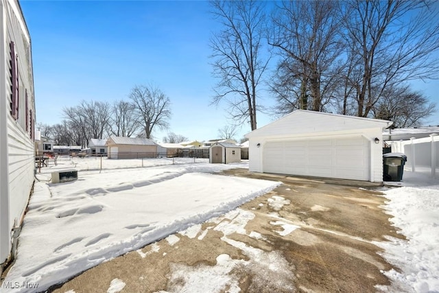 view of snow covered exterior featuring a garage and a shed