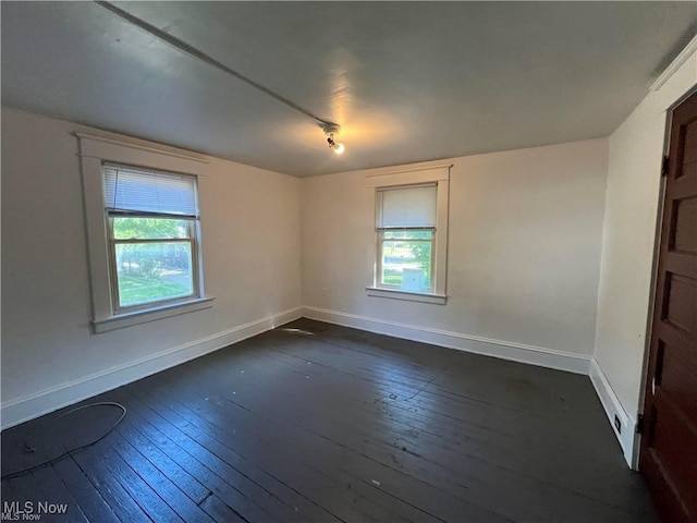 spare room featuring a healthy amount of sunlight and dark wood-type flooring