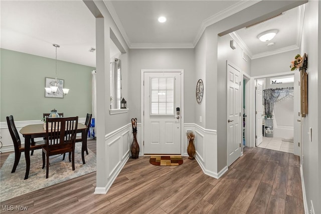 entrance foyer with dark wood-type flooring, crown molding, and a chandelier