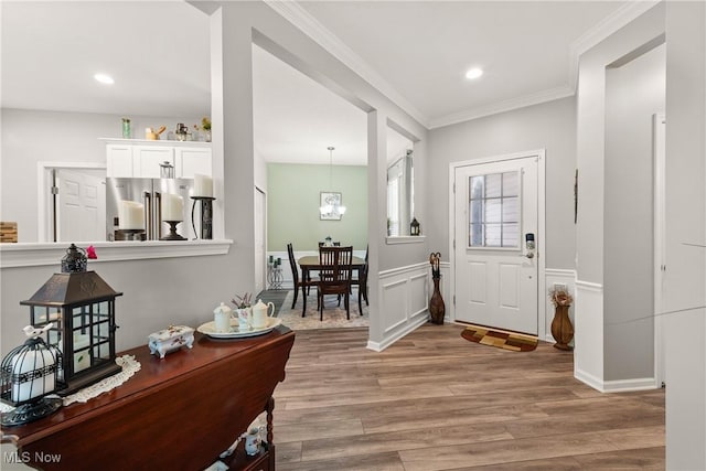 foyer featuring light hardwood / wood-style flooring, ornamental molding, and an inviting chandelier