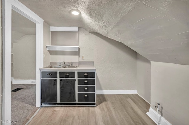 bar with sink, a textured ceiling, lofted ceiling, and carpet