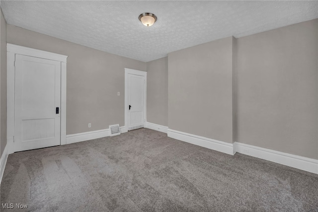 unfurnished room featuring a textured ceiling and carpet