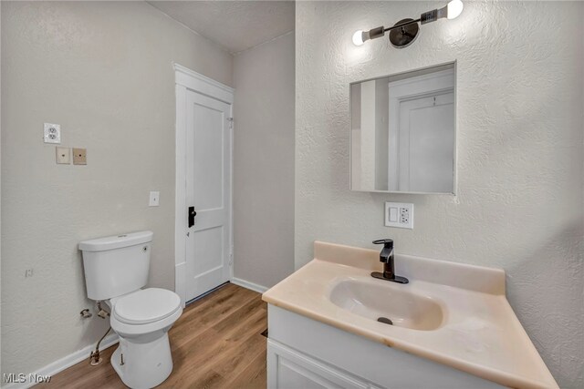 bathroom featuring toilet, vanity, and hardwood / wood-style flooring