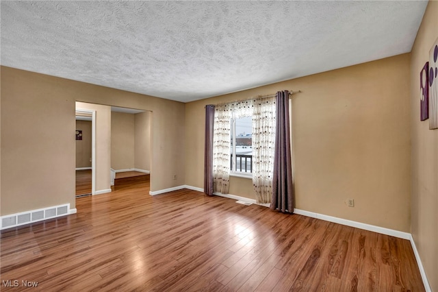 unfurnished room with wood-type flooring and a textured ceiling