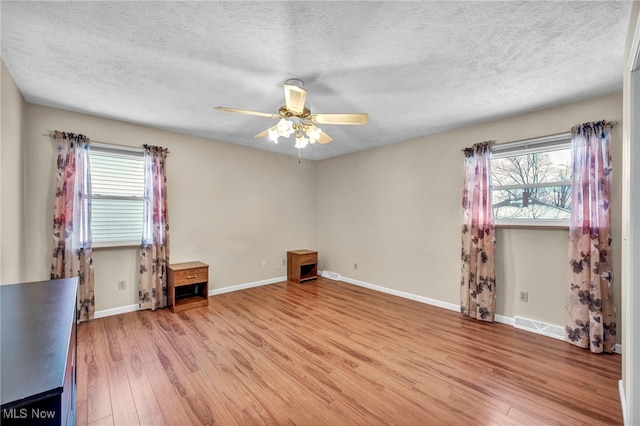 spare room featuring ceiling fan, light hardwood / wood-style flooring, and a textured ceiling