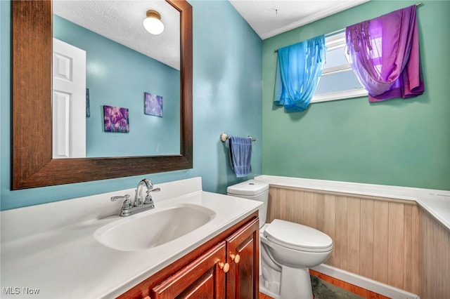 bathroom featuring a textured ceiling, vanity, and toilet