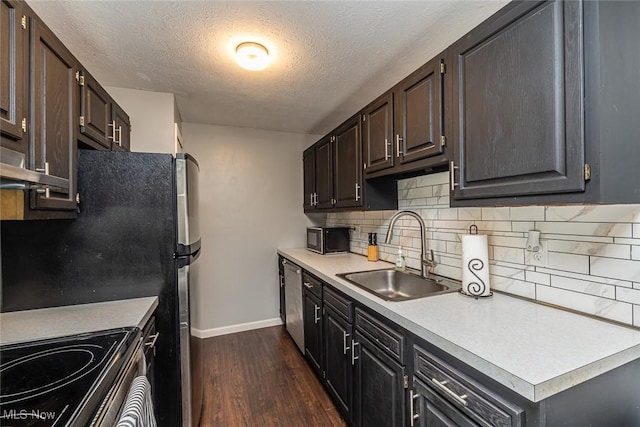 kitchen with sink, a textured ceiling, dark wood-type flooring, tasteful backsplash, and appliances with stainless steel finishes