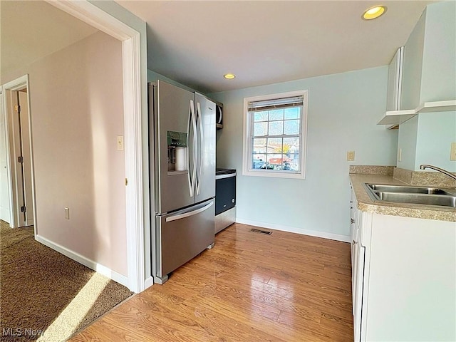 kitchen featuring stainless steel appliances, white cabinetry, light hardwood / wood-style flooring, and sink