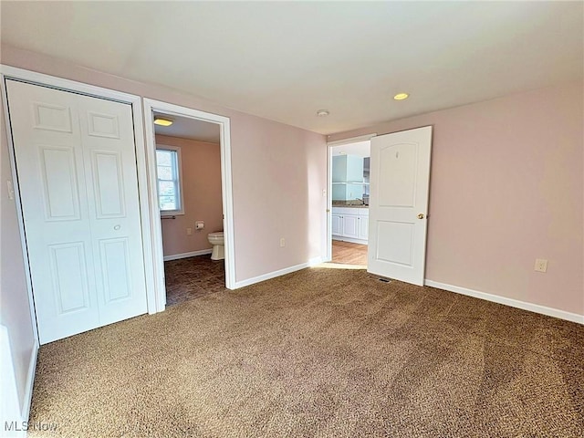 unfurnished bedroom featuring ensuite bathroom, a closet, and carpet flooring