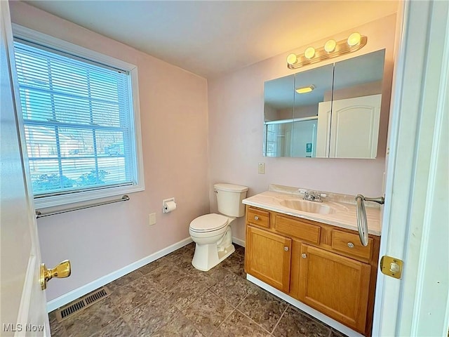 bathroom featuring a shower with shower door, vanity, and toilet