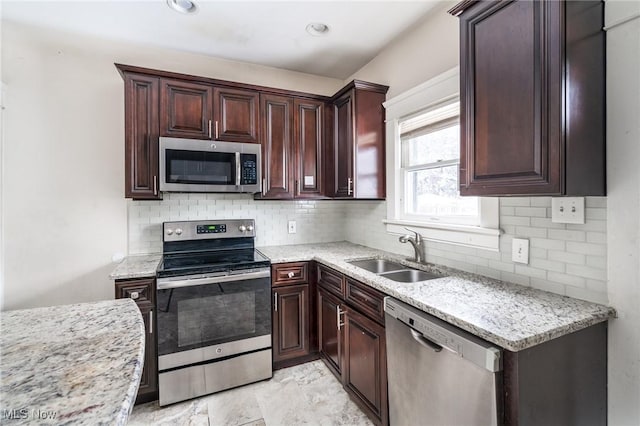 kitchen featuring stainless steel appliances, sink, tasteful backsplash, and light stone countertops