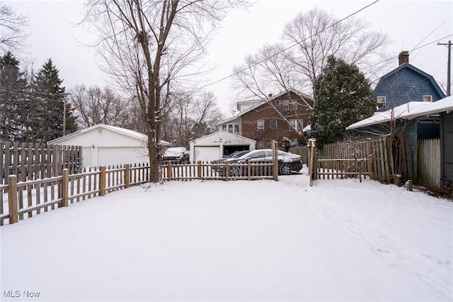 snowy yard featuring a garage and an outbuilding