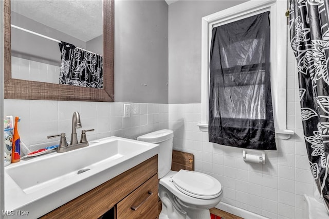 bathroom featuring toilet, vanity, a shower with curtain, tile walls, and a textured ceiling