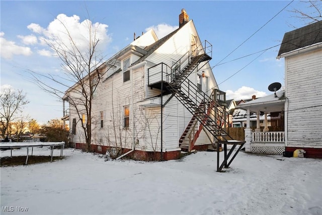 view of snowy exterior with a porch and a trampoline