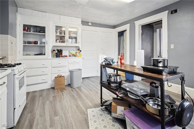 kitchen featuring light hardwood / wood-style flooring, white cabinetry, white range with gas cooktop, and a drop ceiling