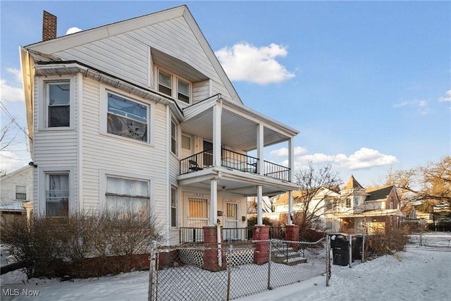 snow covered property featuring a porch and a balcony