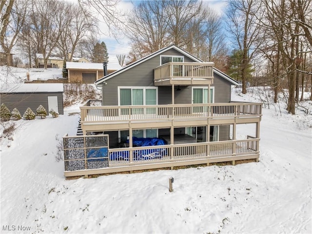 snow covered property with a balcony and a deck