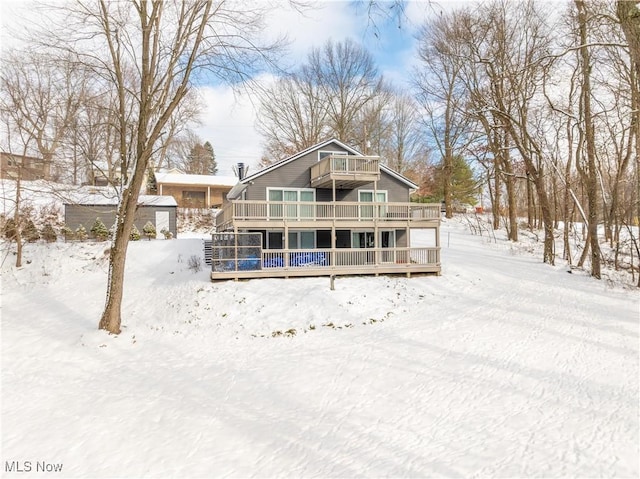 snow covered back of property with a wooden deck