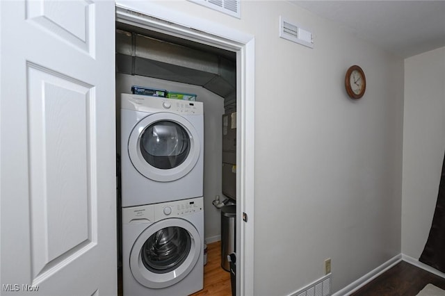 laundry room featuring dark hardwood / wood-style flooring and stacked washer / drying machine