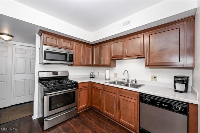 kitchen with appliances with stainless steel finishes, dark wood-type flooring, and sink