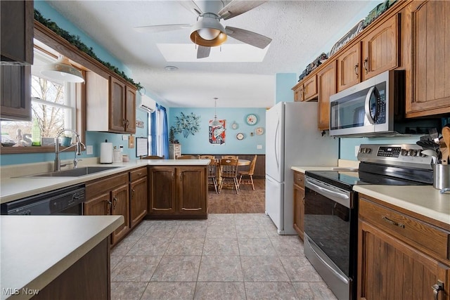 kitchen with kitchen peninsula, a textured ceiling, hanging light fixtures, appliances with stainless steel finishes, and sink