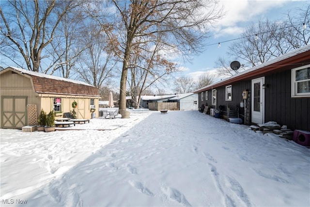 yard covered in snow with a storage shed