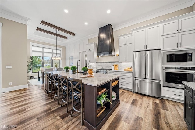 kitchen featuring high quality appliances, white cabinets, a center island with sink, and custom exhaust hood