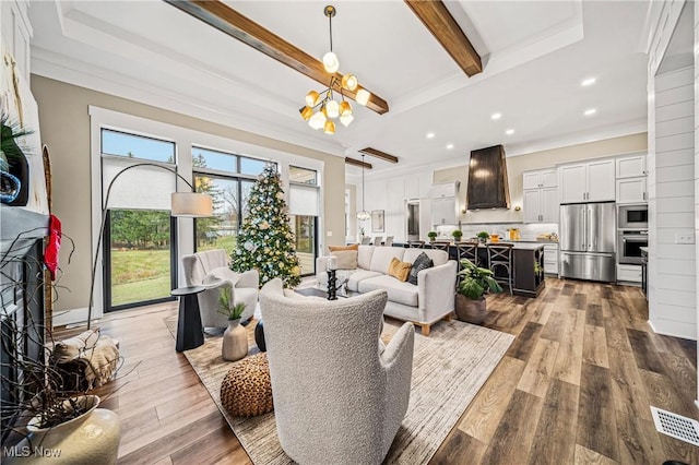 living room with beam ceiling, light hardwood / wood-style flooring, an inviting chandelier, and ornamental molding