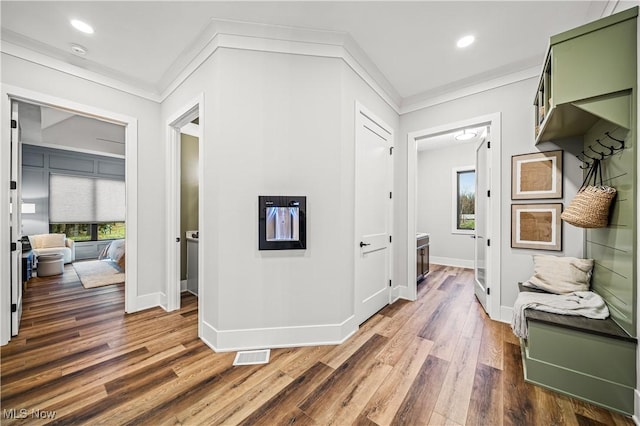 corridor with dark hardwood / wood-style flooring, ornamental molding, and a wealth of natural light