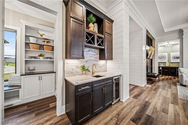 bar with wine cooler, light stone countertops, dark hardwood / wood-style floors, sink, and dark brown cabinets