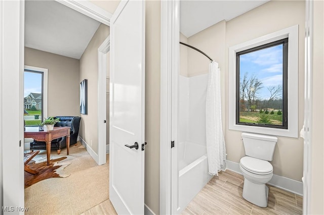 bathroom featuring toilet, shower / bath combo, and a wealth of natural light