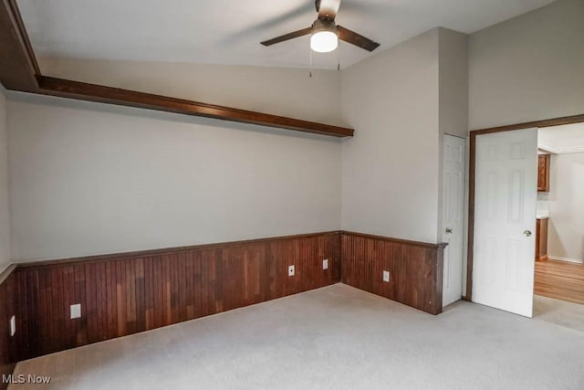 carpeted spare room with ceiling fan and vaulted ceiling