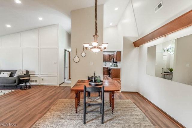 dining area featuring high vaulted ceiling, a notable chandelier, and light hardwood / wood-style flooring