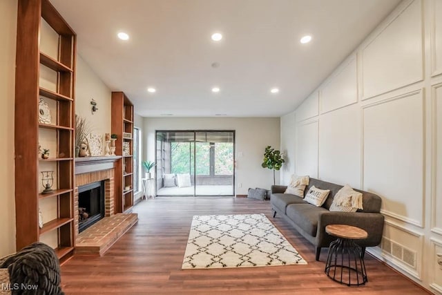 living room with dark wood-type flooring and a brick fireplace