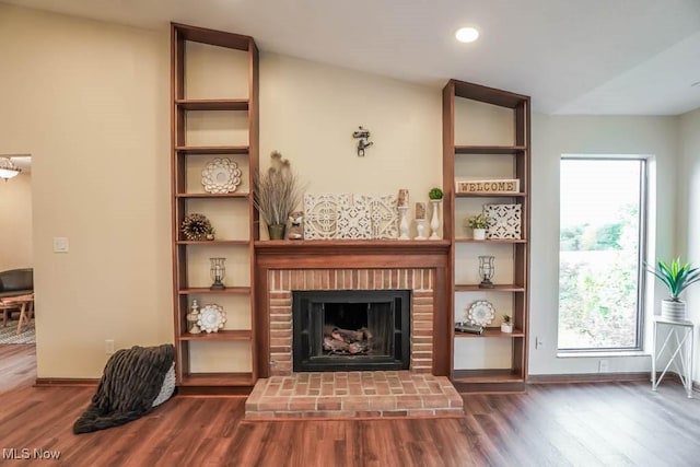 living room with dark wood-type flooring, a brick fireplace, and lofted ceiling