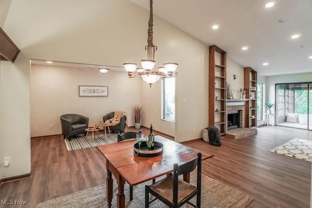 dining room featuring dark hardwood / wood-style flooring, an inviting chandelier, lofted ceiling, and a fireplace