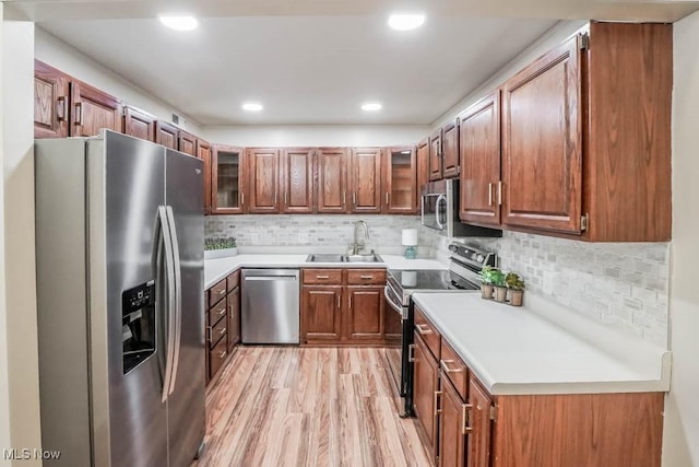 kitchen with appliances with stainless steel finishes, light hardwood / wood-style floors, backsplash, and sink