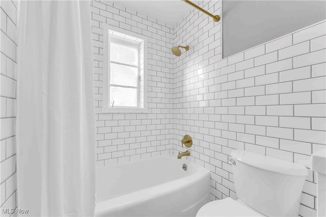 bathroom featuring tile walls, shower / bathtub combination with curtain, and toilet