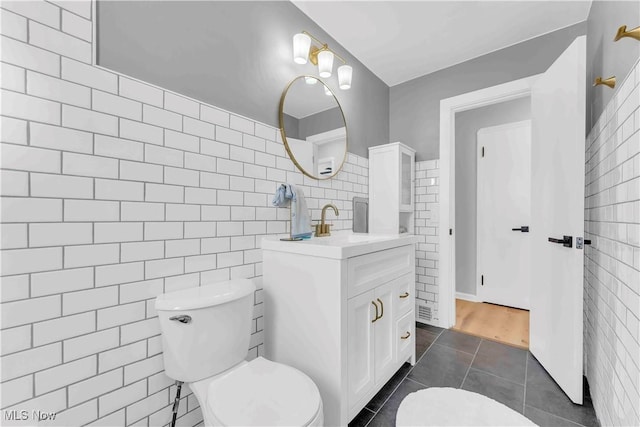 bathroom with tile walls, tile patterned flooring, vanity, and toilet