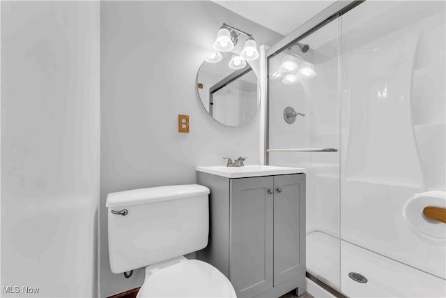 bathroom with toilet, a shower with door, and vanity