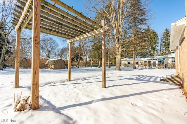 snowy yard featuring a pergola and a storage shed